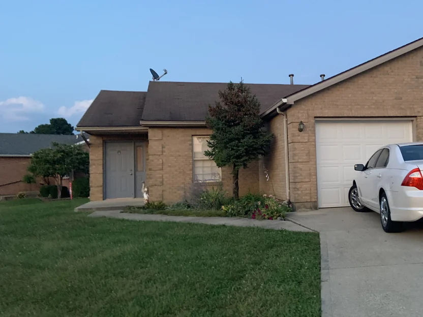 The front of the house from the driveway in 2019, the recessed entry and the garage wing meeting in a single brick range