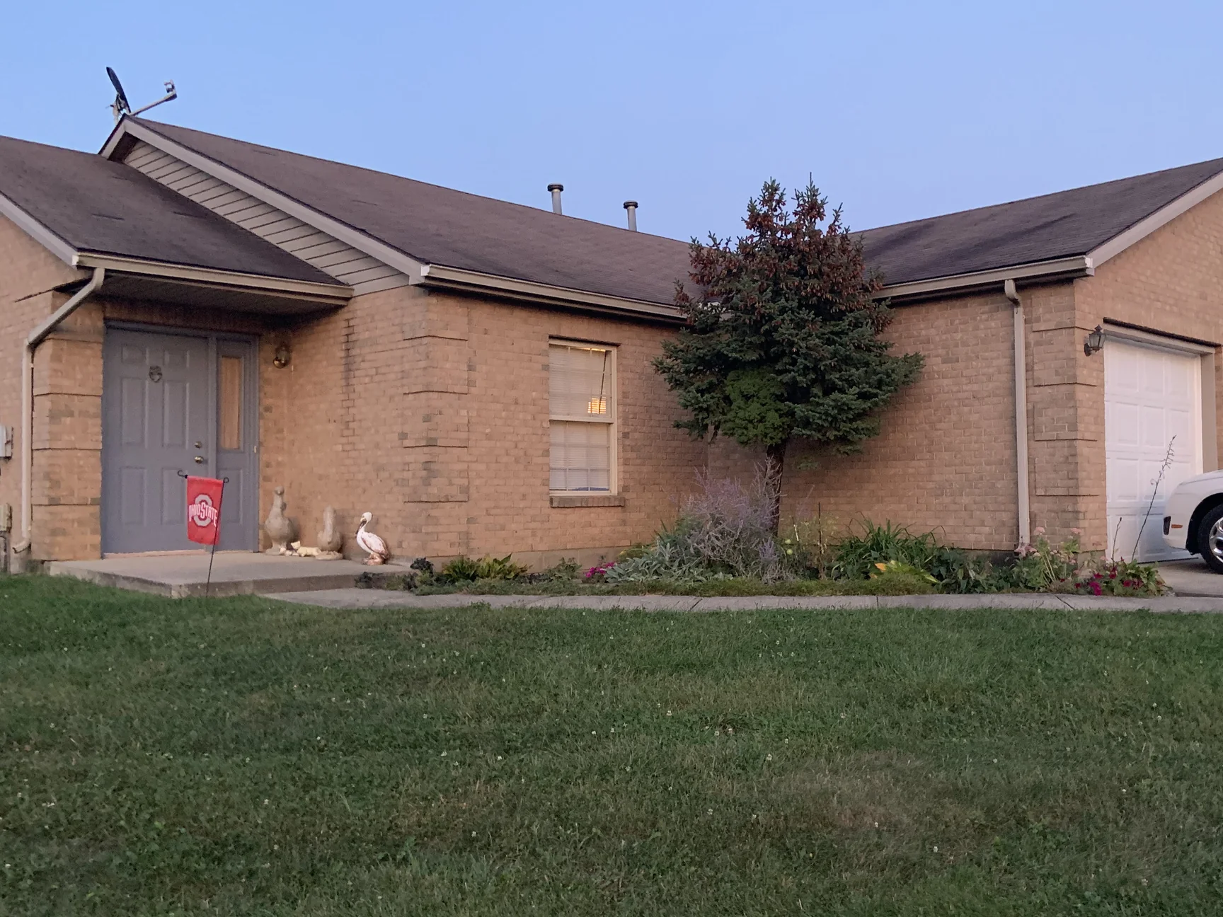 The house seen from across the front lawn in 2019, the entry, the window bay and the garage wing all in one tan brick range