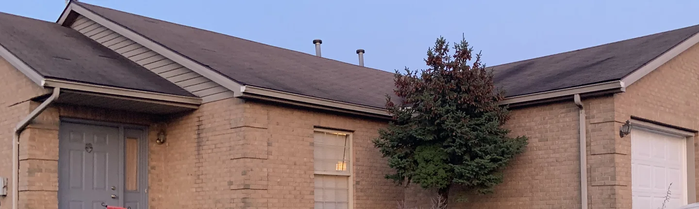 The front of a single story brick ranch house in Ohio in 2019, its brick one even tan range across the entry and the garage wing
