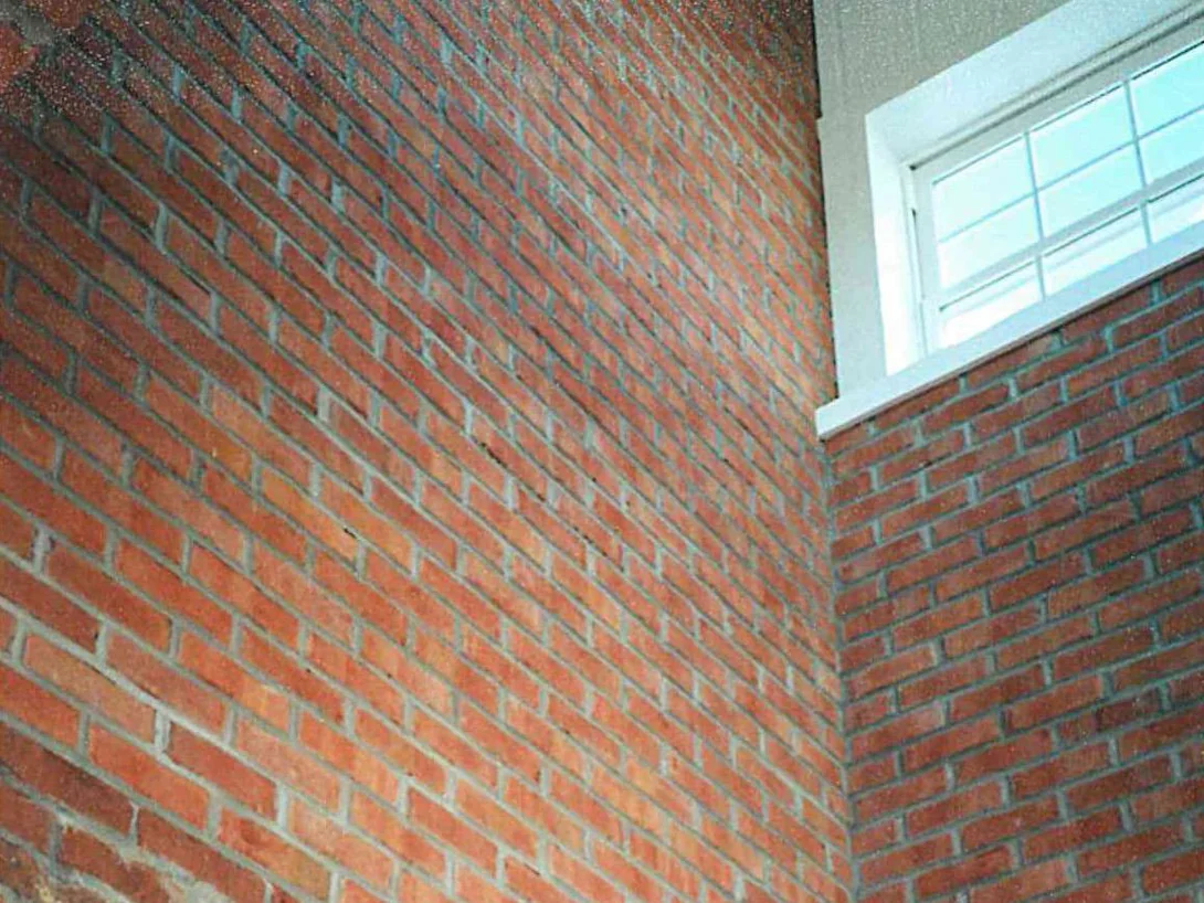 Close view of the brick at an inside corner under the entry canopy in 1997, several units reading darker and patchier than the wall around them