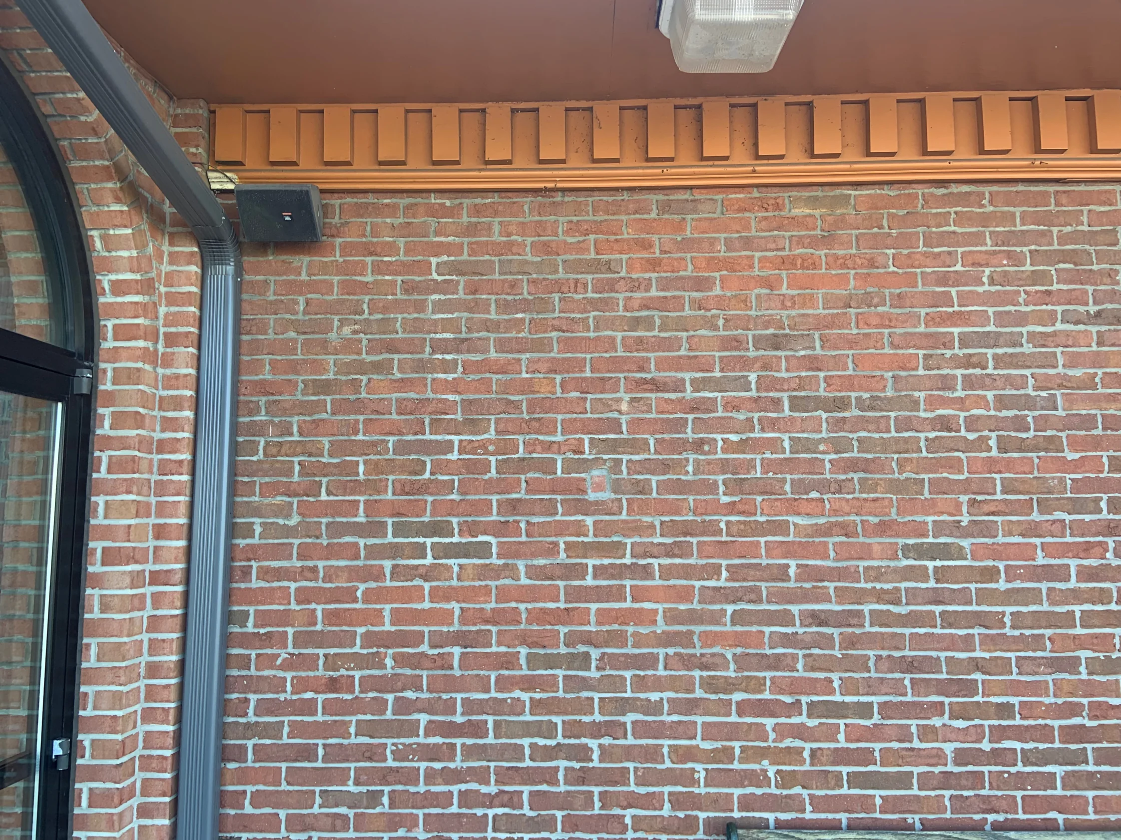 Close view of the brick under the entrance canopy in 2019, an even red and brown range running up to a projecting dentil course