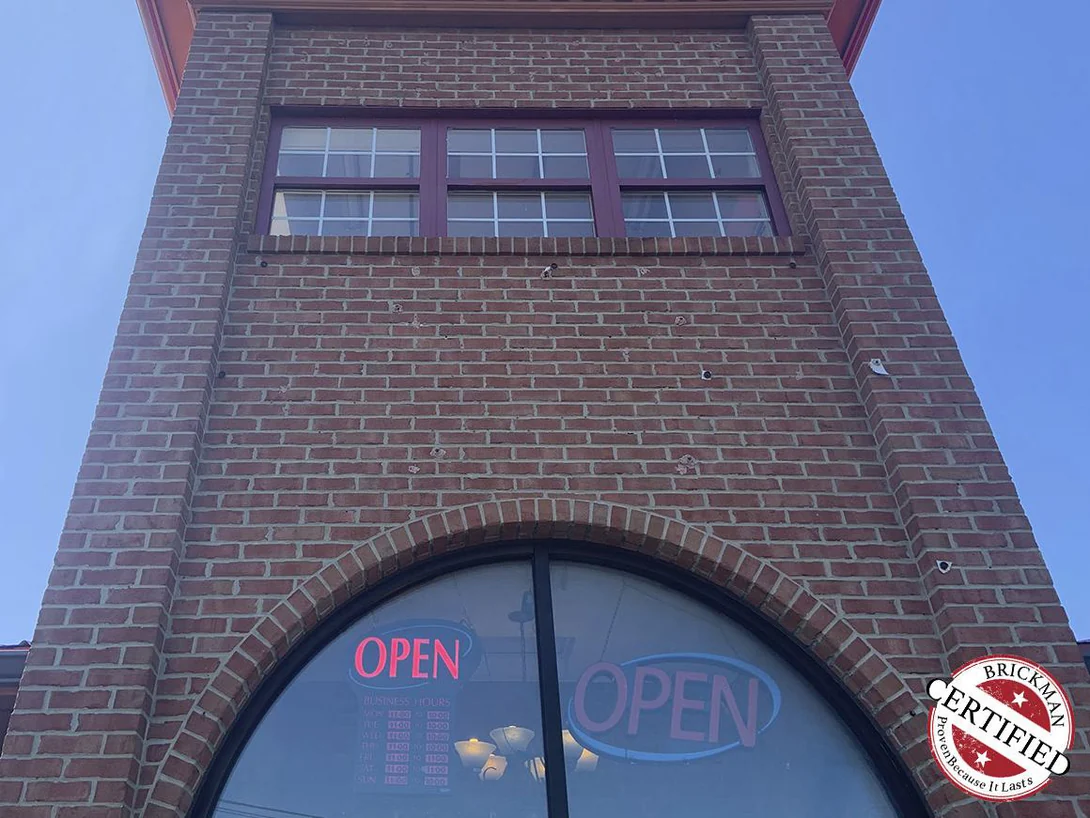The entry tower seen from below in 2019, the brick an even red range from the arched window up to the dentil course