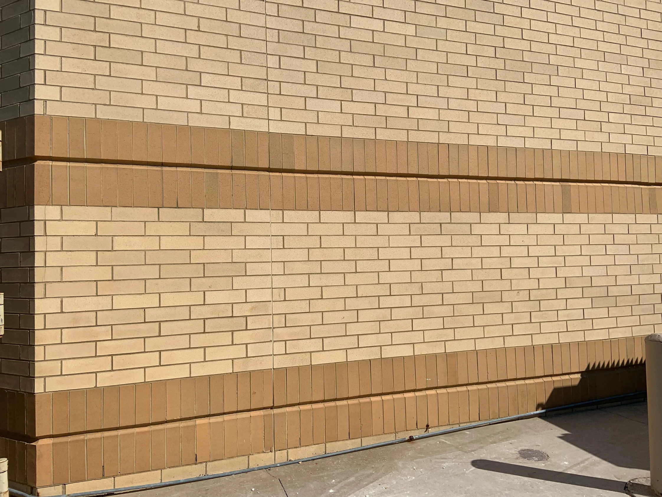 An outside corner of the mall in 2019, two bands of tan soldier brick running across both faces above and below a field of buff brick