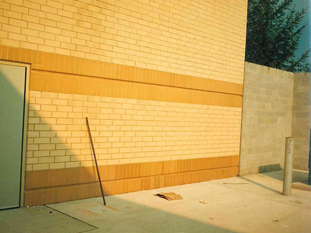 A pair of service doors in 1996 set in buff brick, with a wide orange soldier band across the wall and a second band at the base