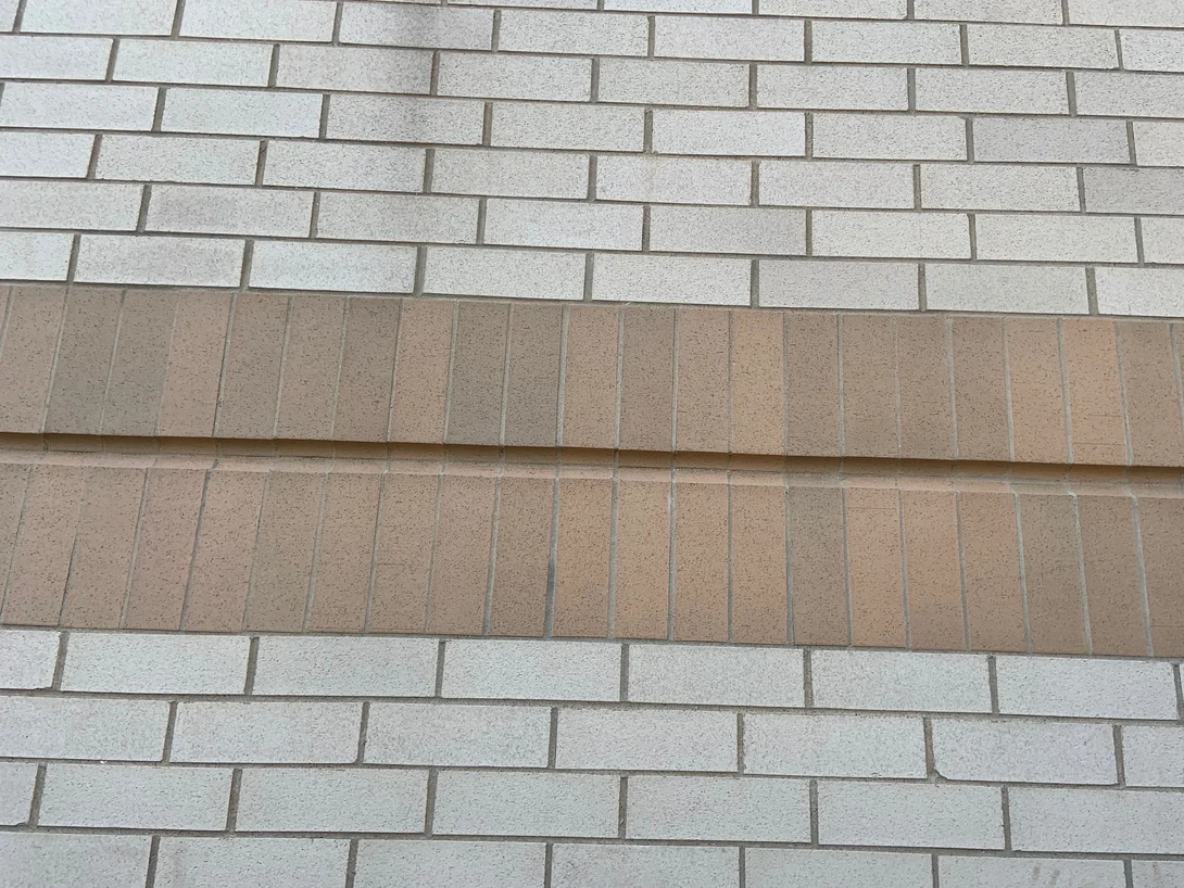 Close view of the two tan soldier courses in 2019, the upright units reading as one range against the buff brick around them