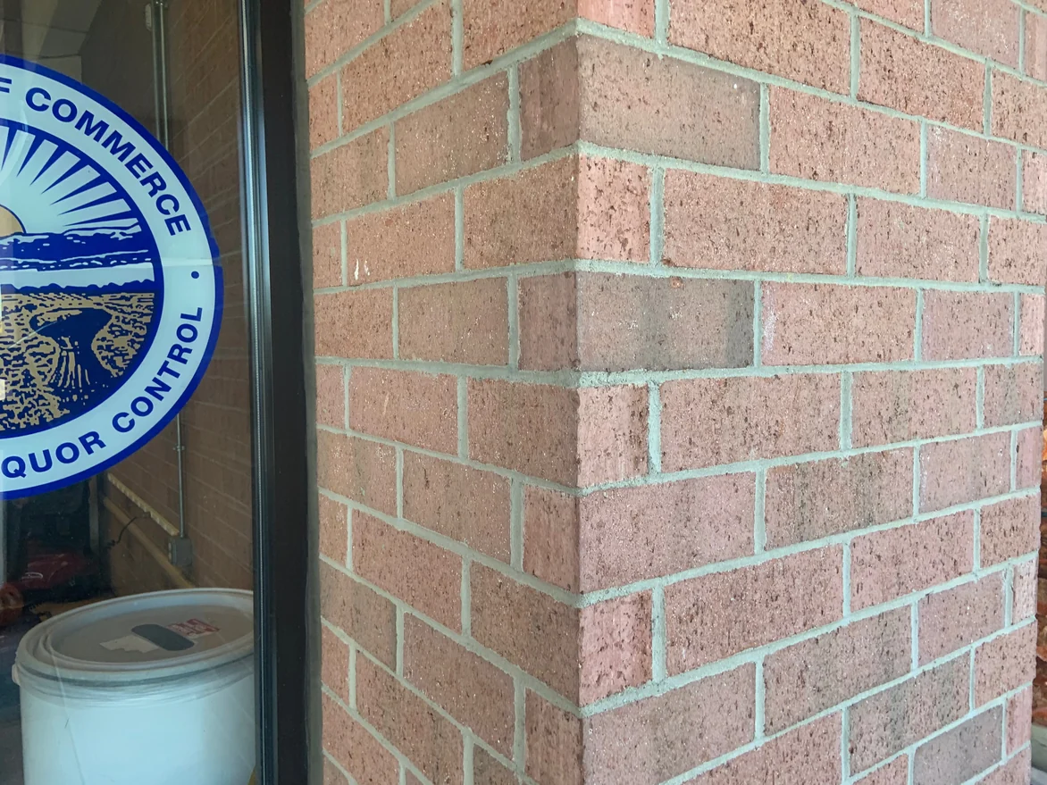 An outside brick corner of the store in 2019, the units on both faces reading as one pink and red range