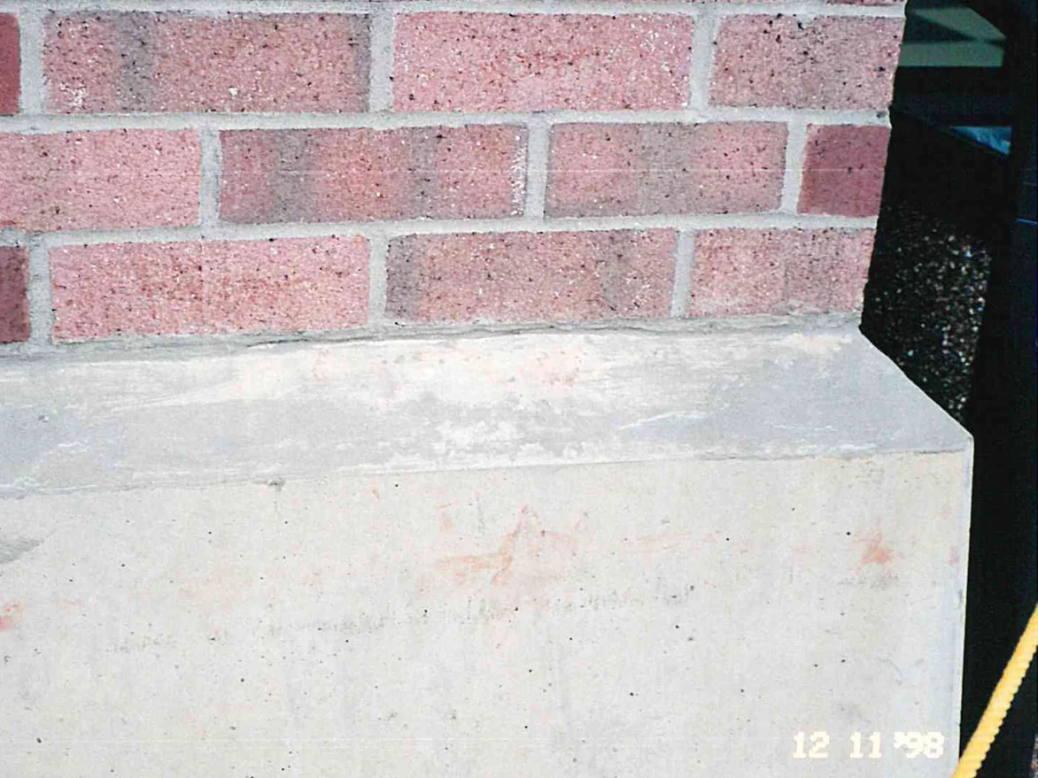 Close view of the lowest courses of a brick pier above its concrete base in 1998, the units a range of pale pink and darker red