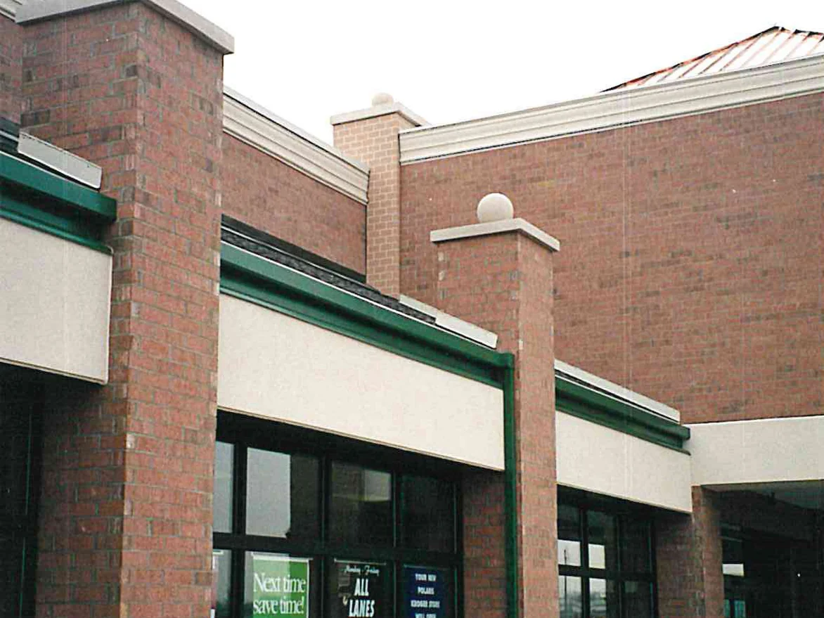 The storefront and brick piers of the grocery store in 1998, a window sign in the glass announcing the store opening that December