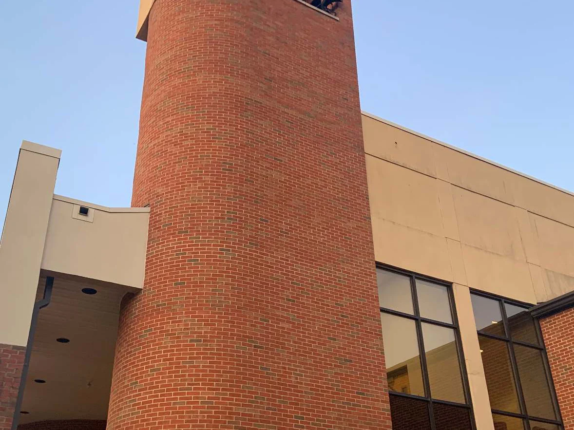 The curved brick stair tower in 2019 seen from below, radial brick winding around the drum in one red range beside cream panelled walls