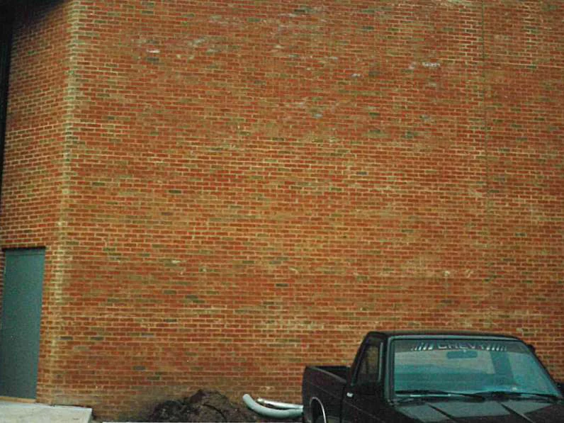 The blank end wall in 1998 with bare dirt and a pickup truck at its foot, patches of paler and greyer brick scattered through the red range