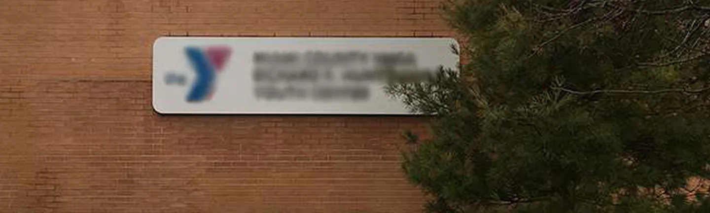The wall of the Ohio youth center in 2019, brick running as one even range past the building sign to a pine at the corner