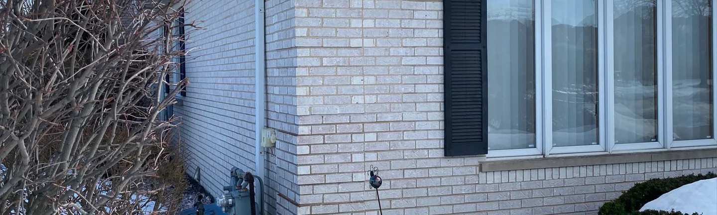 The corner of the Orland Park home in 2021, pale brick and light mortar reading as one range across both walls