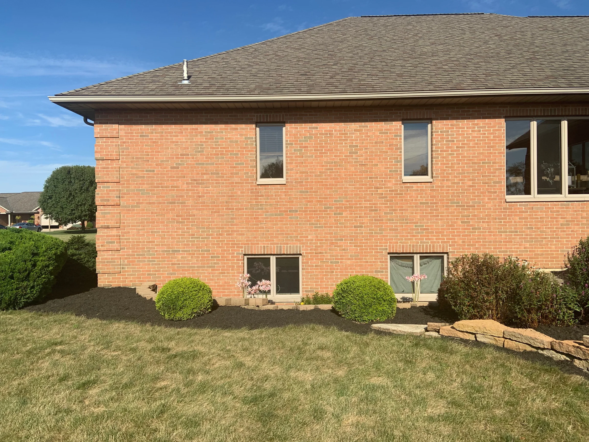 A tall end wall of the house in 2019, the brick running one even range from the lower windows to the eaves with a projecting quoin at the corner