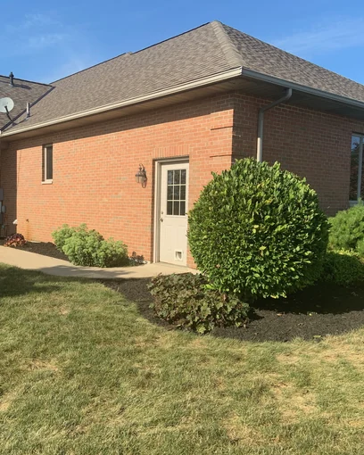 The back of a single-story house in Osgood, Ohio in 2019, its red brick one even range seventeen years after staining