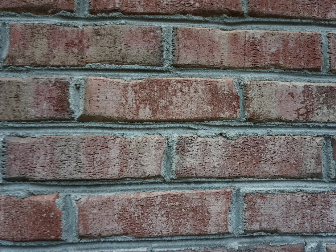Close view of five courses of brick in 2019, the faces mottled red, salmon and cream unit to unit over grey mortar