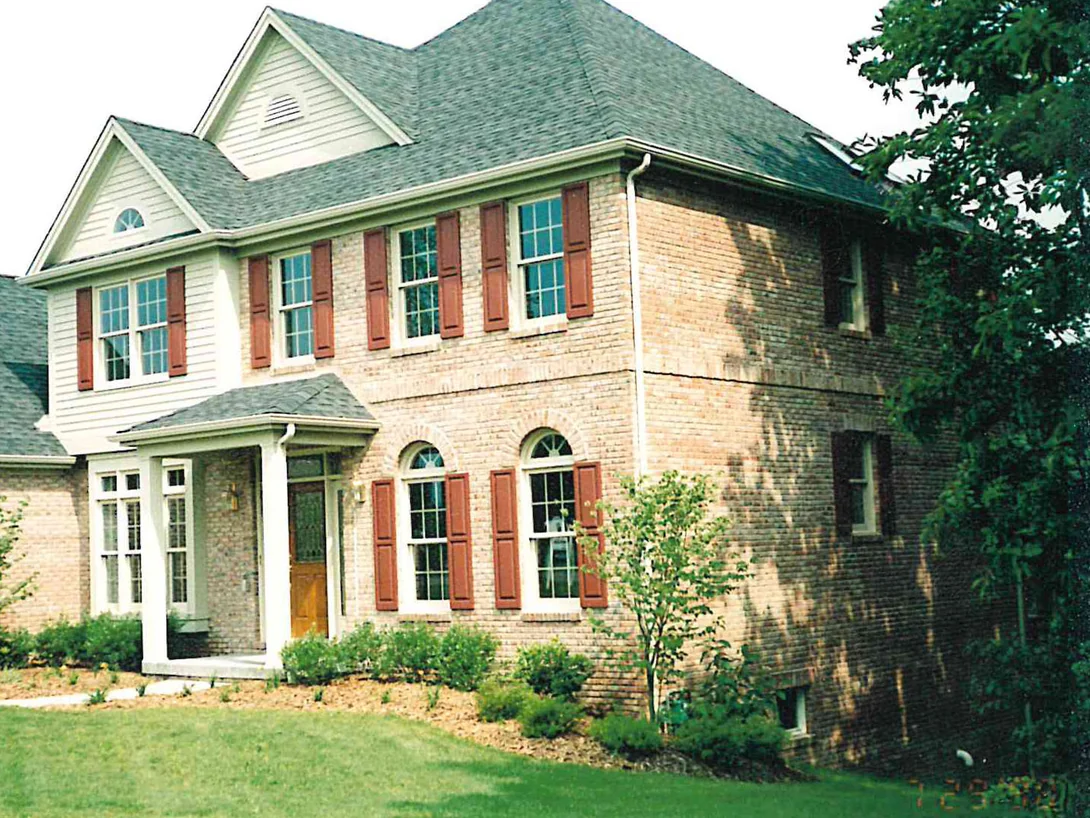 The front of the two-story house in 1998, its brick reading pale buff with darker mottled areas across the end elevation, arched brick heads over the ground-floor windows