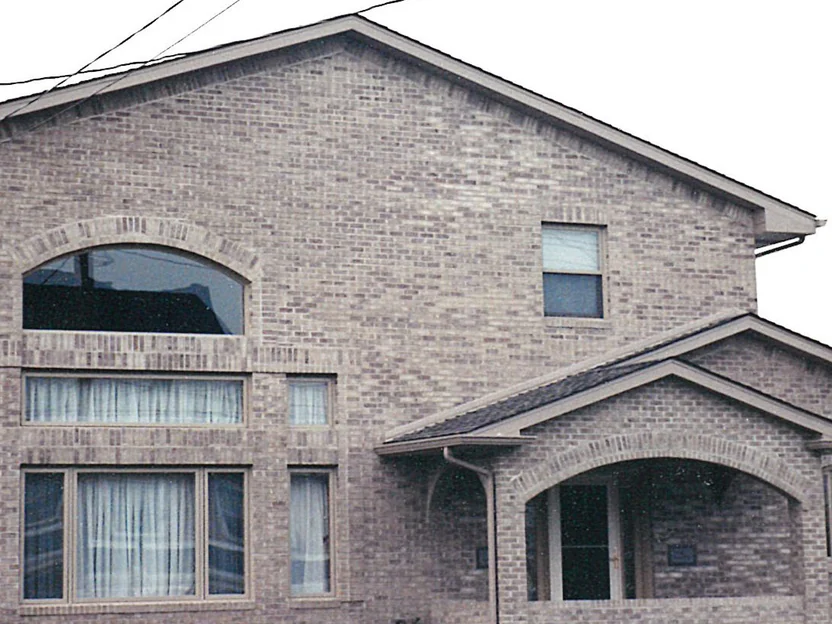 The front gable of the funeral home in 2000, the brick varying in tone from course to course beneath a large arched window