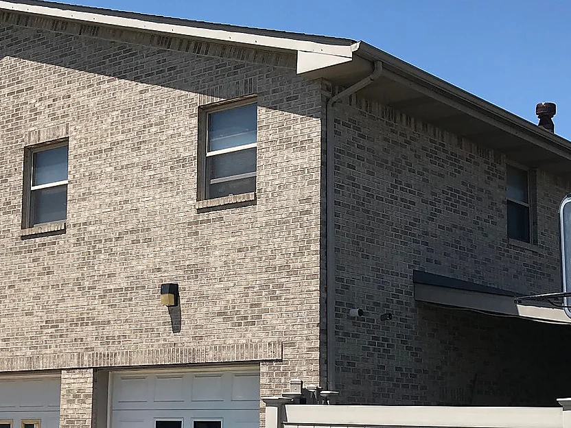 The same side wall in 2019, the brick carrying one even range from the eaves down to the garage doors