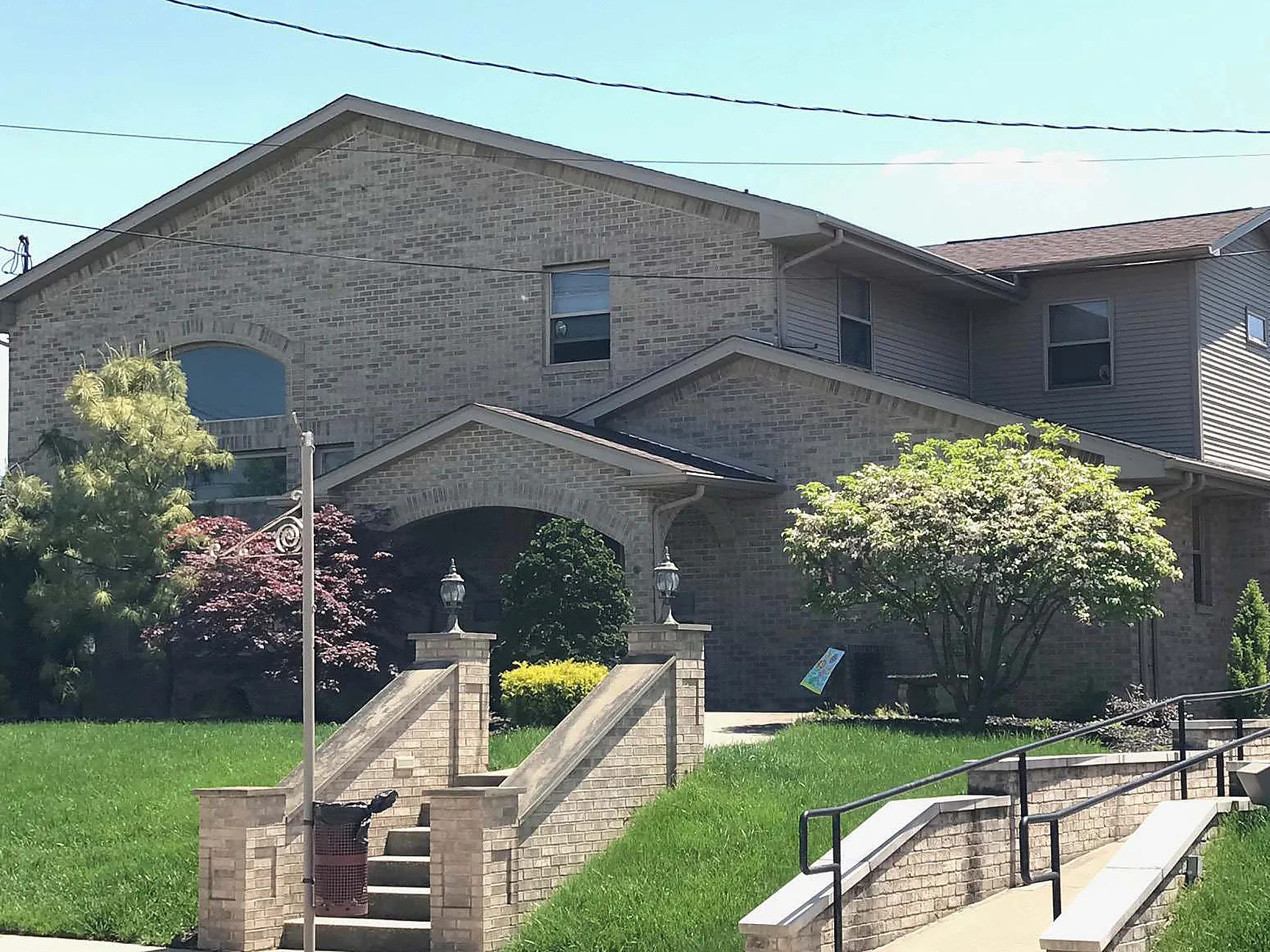 The funeral home seen from the street across its front lawn in 2019, the brick reading as one even range from the gable to the wing beyond