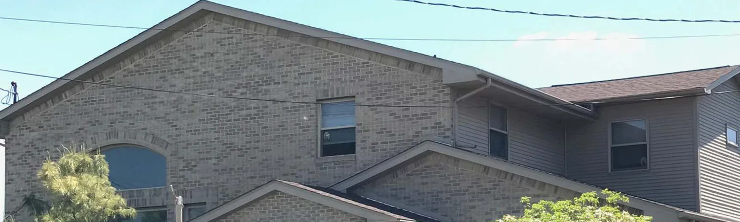 The gable and entrance canopy of a brick funeral home in 2019, the brick reading as one even range