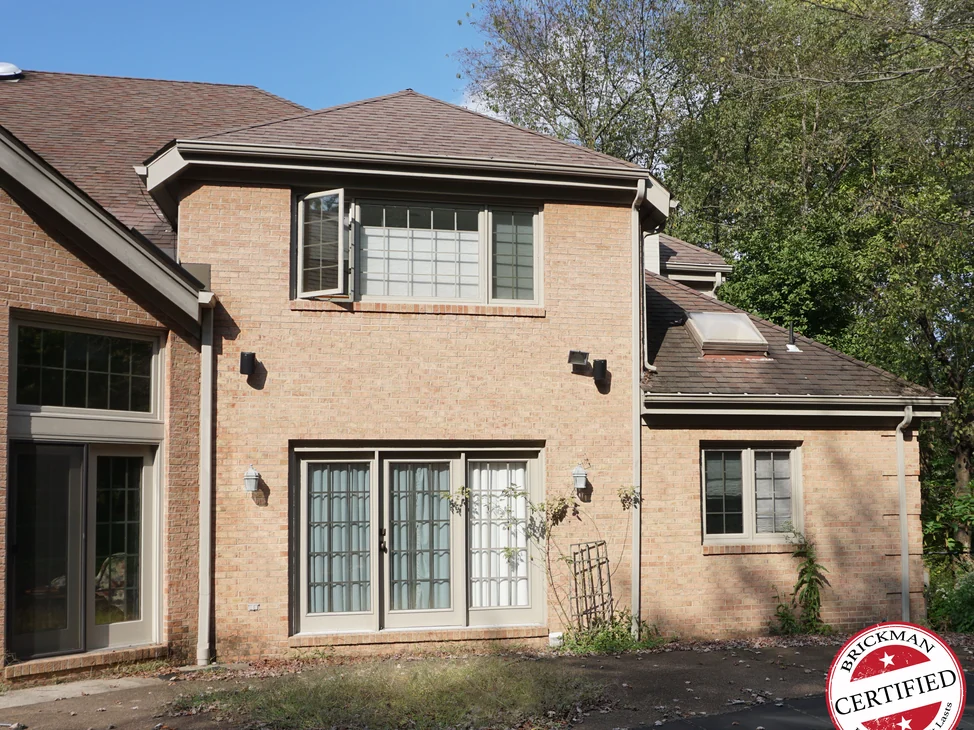 The back of the house in 2019, the two-story projecting section, the french doors and the single-story wing beside them all reading as one even buff and tan range.