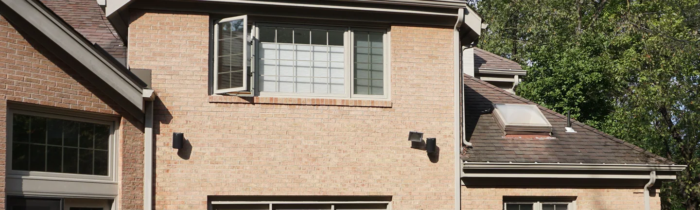 The back of the house in 2019, the two-story section and the wing beside it reading as one even buff and tan range from the eaves down