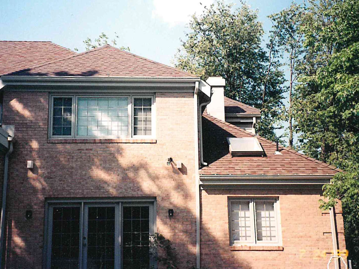 The same back wall later in 1999, seen wider, the brick below the window band now carrying the same range as the wall above it, with the chimney and the lower wing beyond