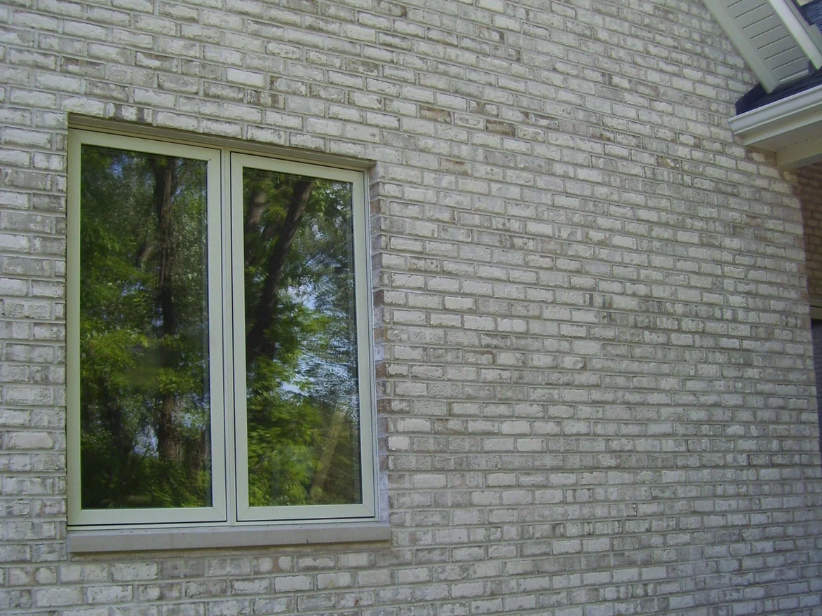 A side wall of the house in 2008, the light brick uneven with grey and tan units breaking up the courses around a single window