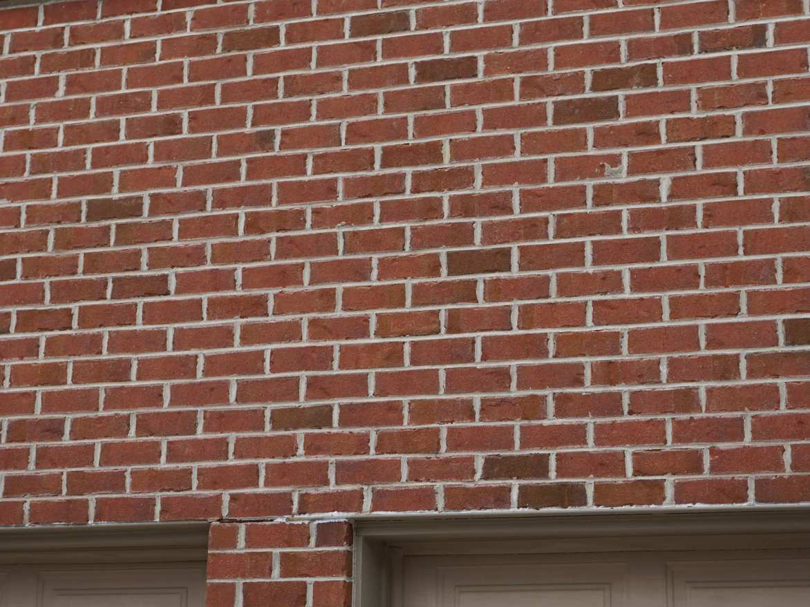 Close view of the brick above the garage doors in 2019, pale mortar stain visible along the edges of individual units