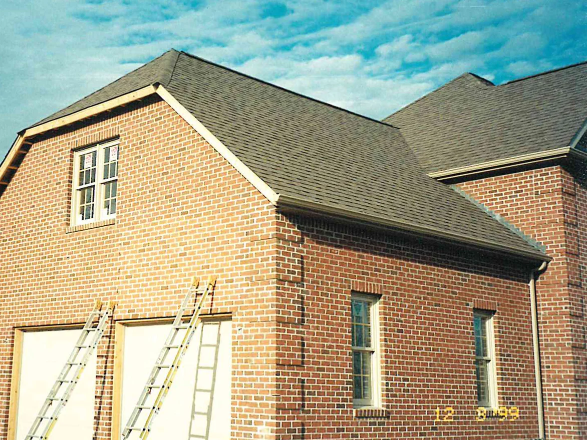 The garage gable end in 1999 with two ladders leaning against it, the new brick a warm red under a wood trimmed roof edge
