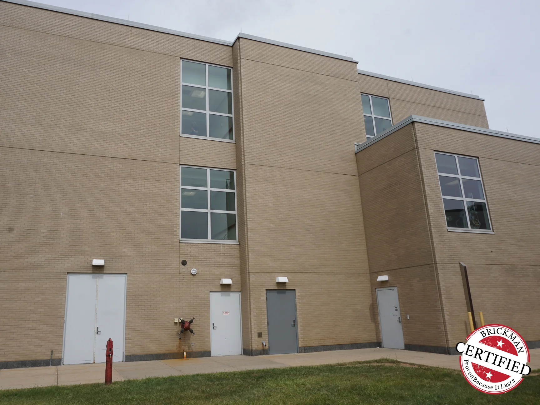 Two storeys of buff brick on the hospital's rear elevation in 2019, with service doors along the ground floor