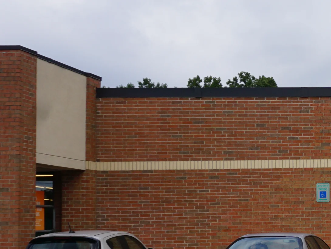 The front corner of the building in 2019 with the elevation running away from it, the brick above and below the cream banding course holding a range of red, orange and tan