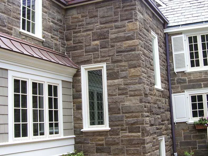 The addition's outside corner in 2006 after staining, its stone carried to the same range as the original wall beyond the downspout