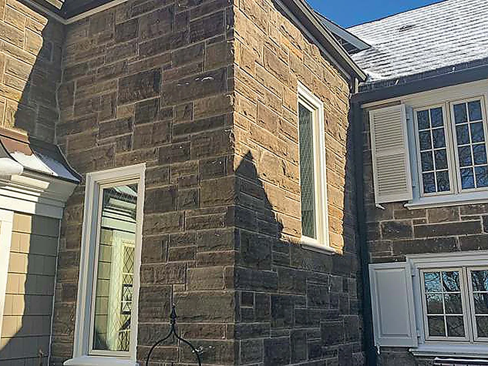 The addition's stone corner in 2021, running to the original stone wall on the right with snow on the slate roof above