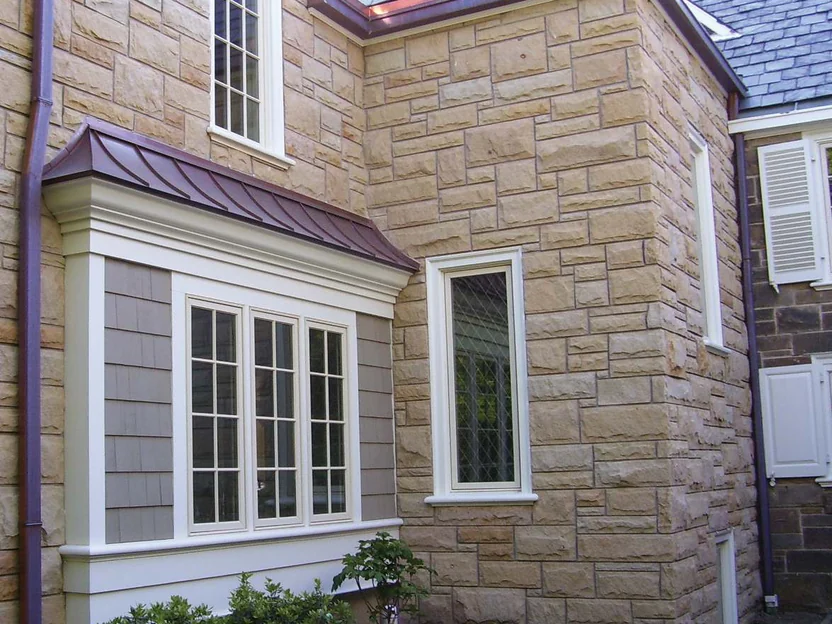 The addition's outside corner in 2006, pale cream stone above a copper roofed bay window, with the darker original stone showing at the right edge