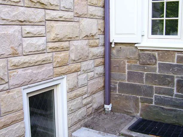 An inside corner in 2006 where the addition's pale cream stone meets the original grey brown stone on the far side of a downspout