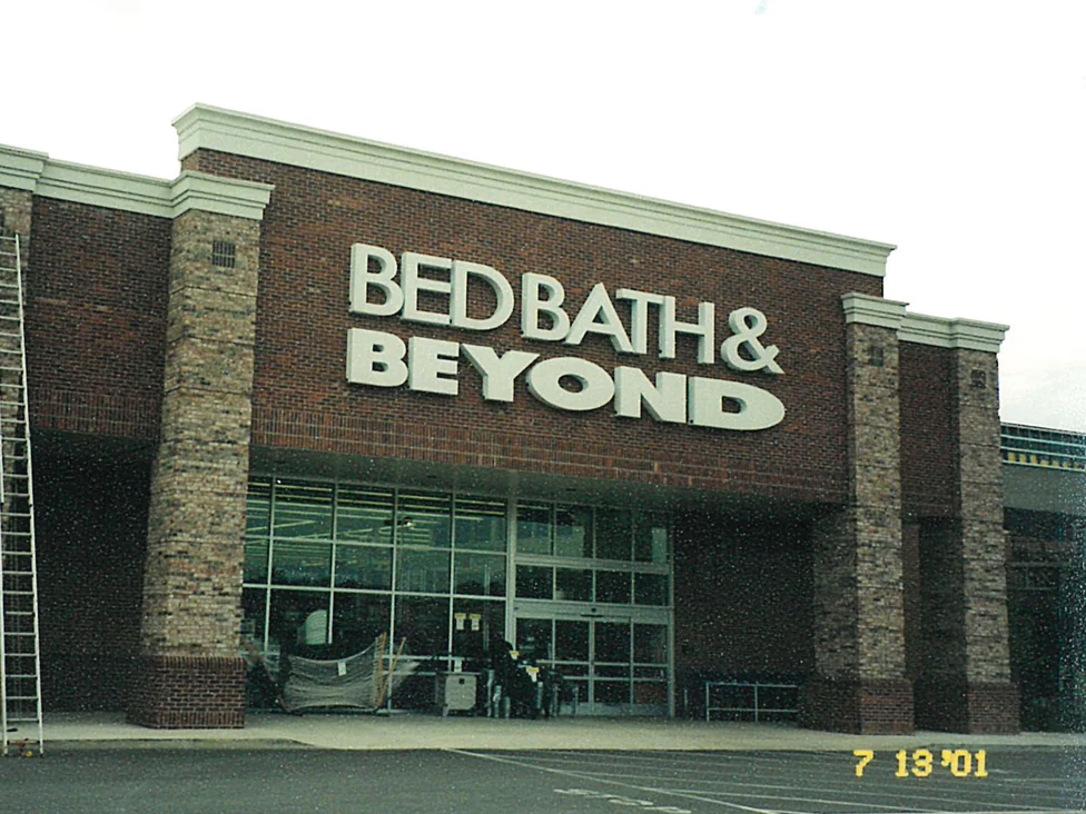 The store entrance in 2001, four piers in pale tan and cream brick standing against a wall of dark red brown brick, with a ladder at the left