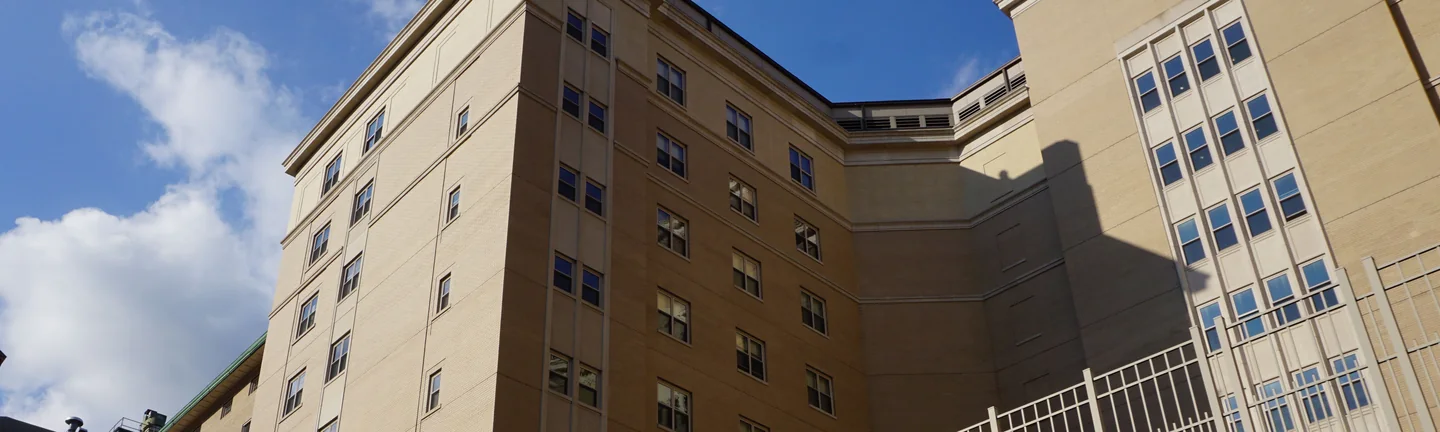 The upper floors of the college building in 2019, tan brick running across the tower and the wing beside it