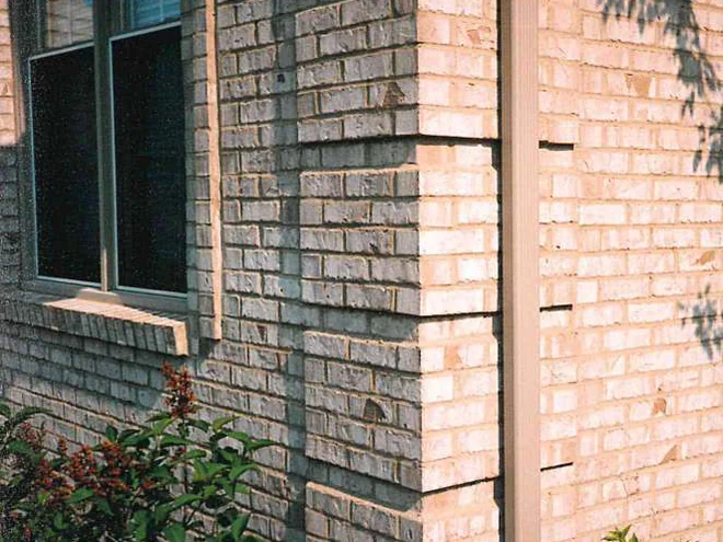 An outside corner beside a window in 1997, the brick showing chipped darker patches on both faces beside a downspout