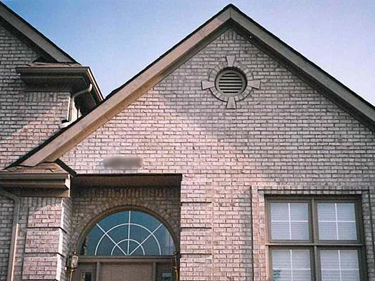 The entry gable of the house in 1997, a pink-cast film scan, an arched transom over the front door and a round louvered vent in the gable, the house number blurred in the file