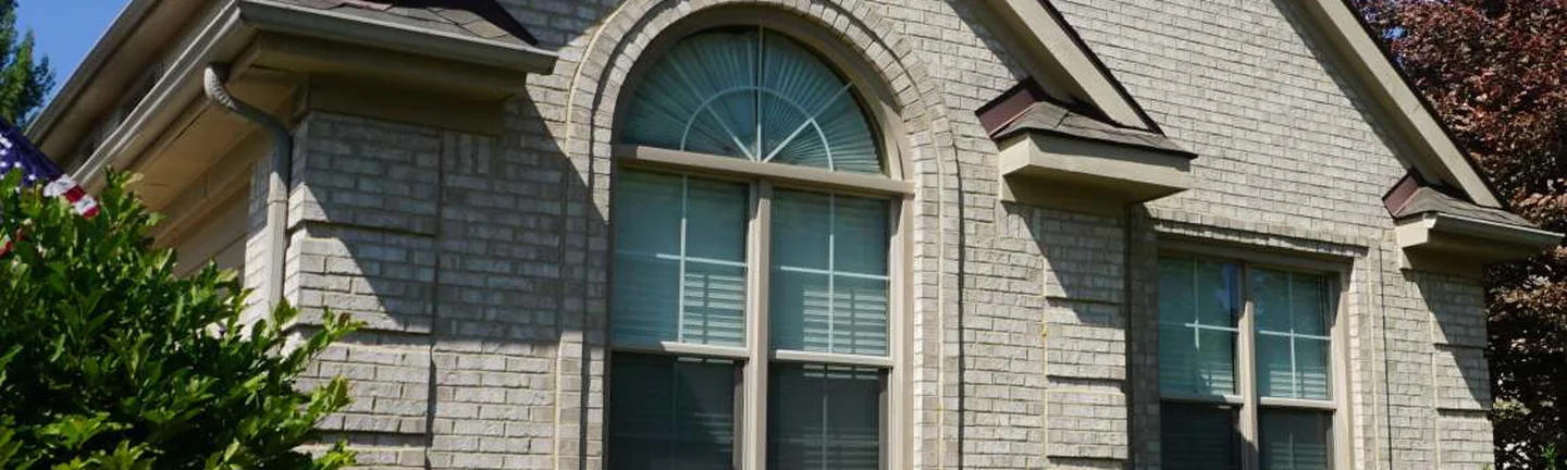 The front gable of the Plymouth house in 2019, pale grey cut and rollback brick around an arched window, the texture reading as one range across the wall