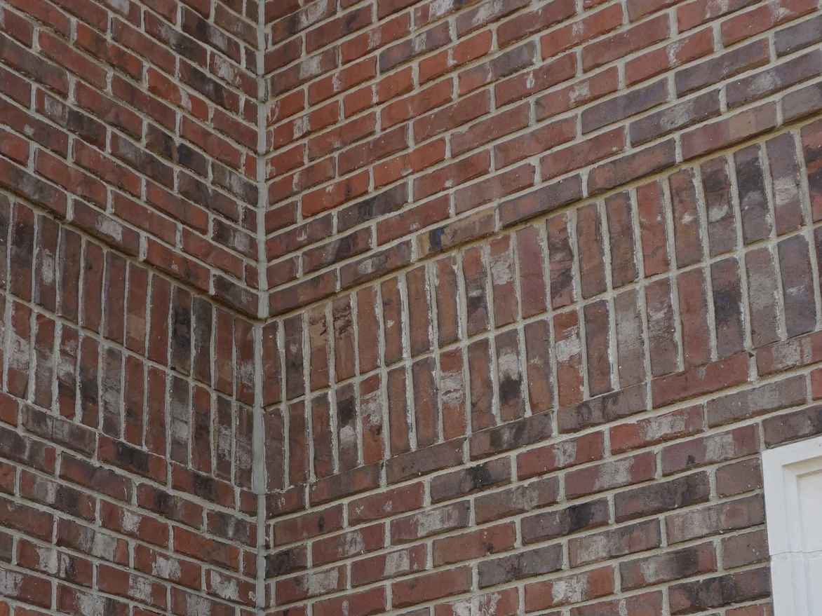 Close view of the blended brick at an outside corner in 2019, an accent course of upright units running across both faces