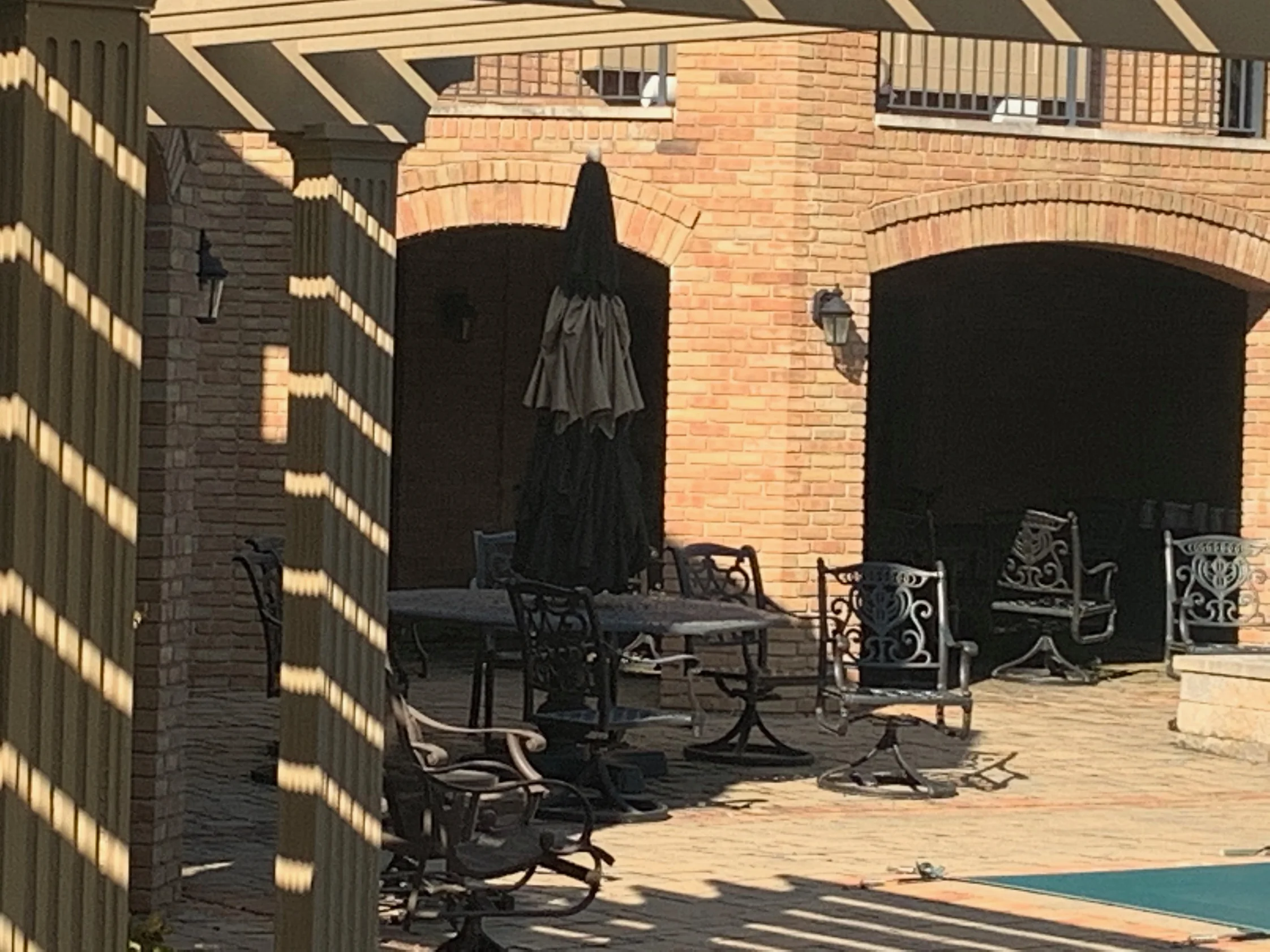 The terrace seen past the pergola posts in 2019, the piers and both arches reading as one warm cream and salmon range