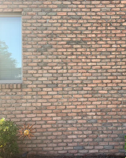 A brick wall and window on an Ohio home in 2019, the once damaged brick reading as one range