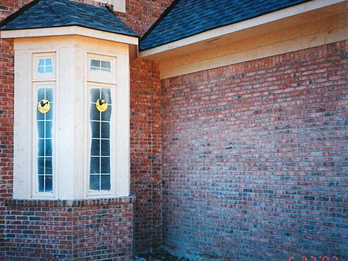 A bay window and the brick return beside it in 1997, the wall to the right running pale and uneven