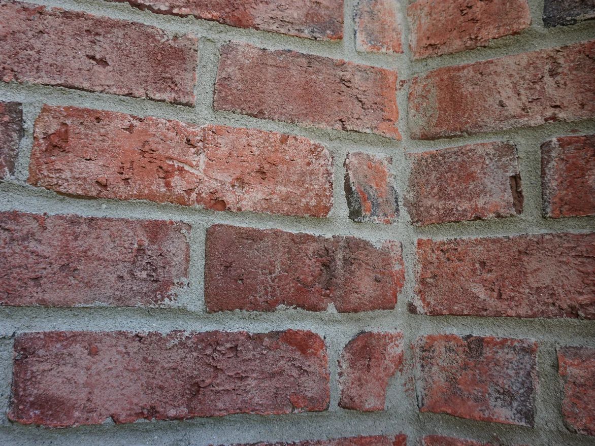 Close view of an outside brick corner, the units in mixed reds and browns with pale mortar joints