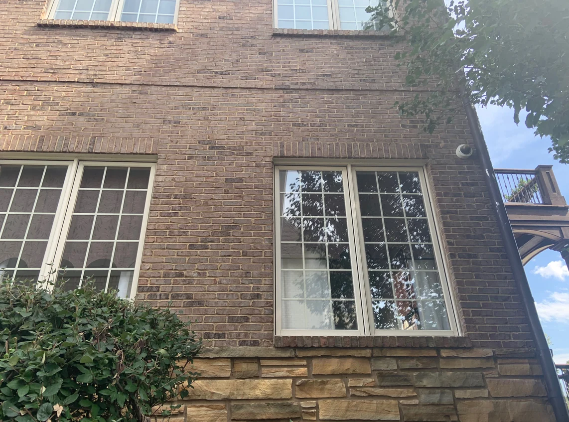 Brick and stone under two windows on an Indiana home in 2019, the brick and mortar stained in 2007 still one wall