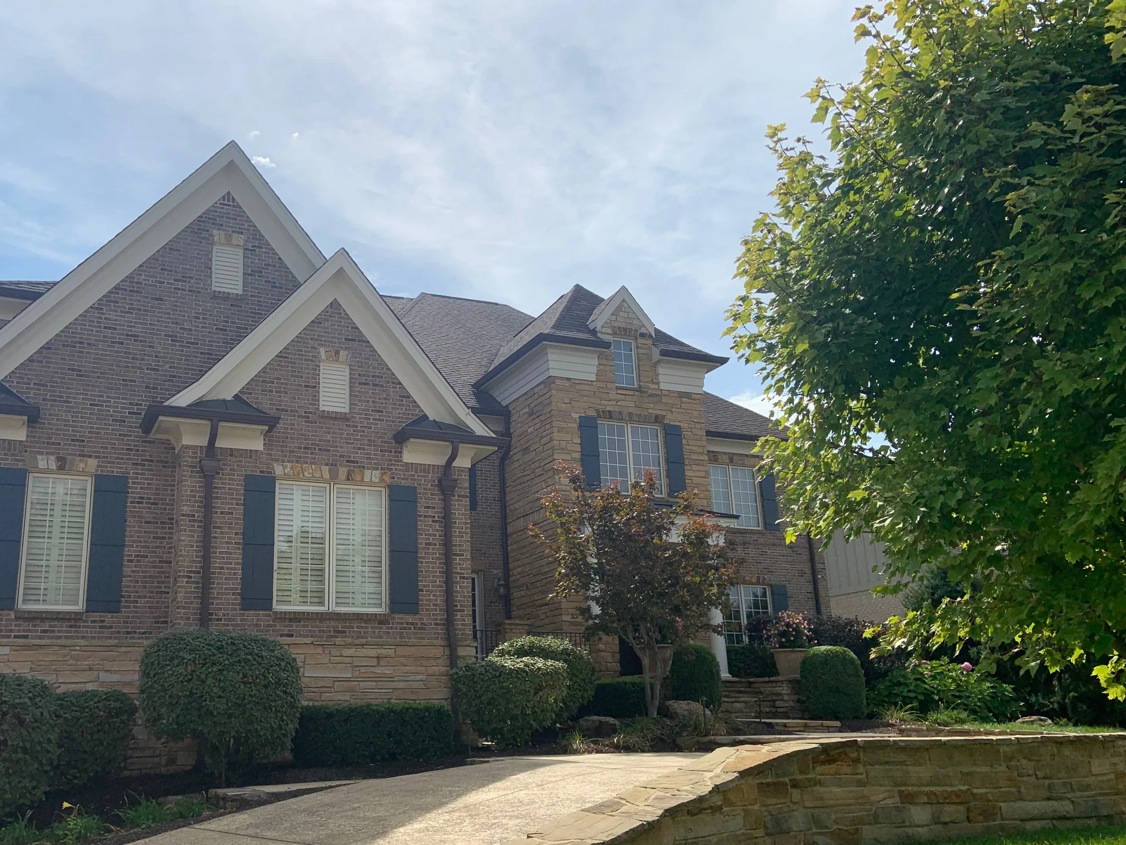 The front of the house in 2019 from the driveway, its twin brick gables and stone bay reading as one settled range under mature planting
