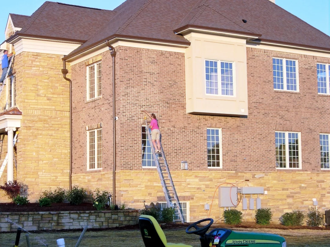 Two applicators on ladders at the side elevation and the entry portico in 2007, the brick reading warm tan against a sandstone corner