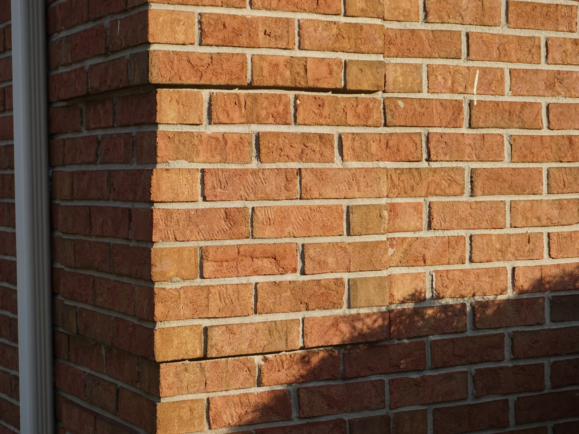 The brick at unit scale on an outside corner in 2019, warm orange and red units with pale mortar joints turning the corner together